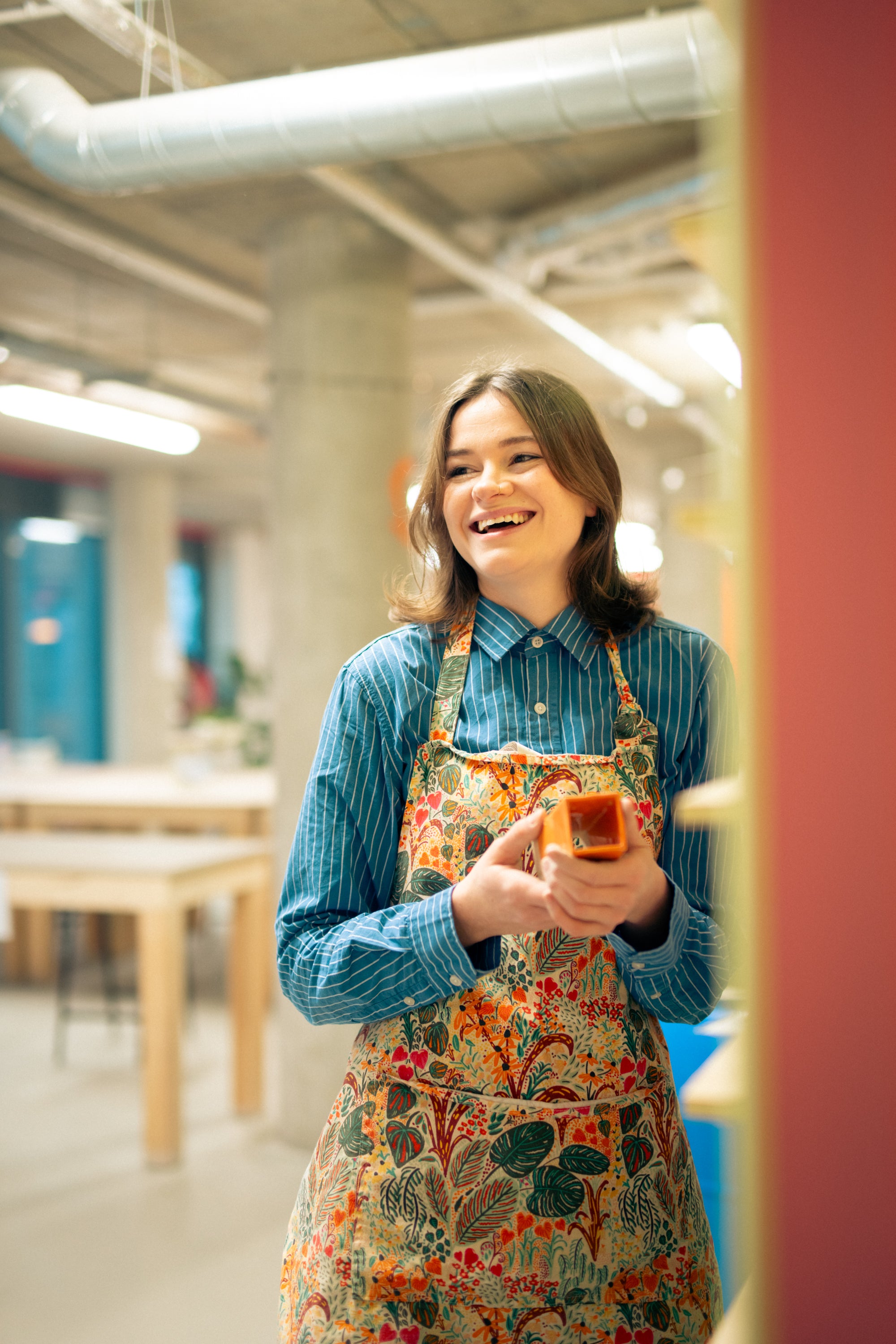 Throwing Shapes teacher Lily smiles as she holds a glazed ceramic cuboid
